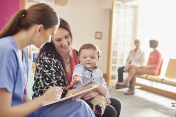 Femme portant un enfant main tendue vers le bloc note d'une femme